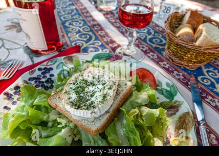 Französische rustikale Vorspeise mit Ziegenkäse Chèvre auf Toast mit Salat und Roséwein im Restaurant Au Bon Accueil, Beaune, Côte d'Or, Frankreich. Stockfoto