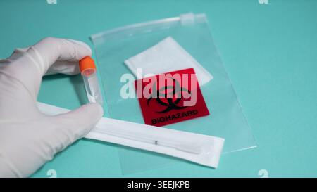 Handschuhe halten PCR-Teströhrchen mit Beutel für biologische Gefahrenstoffe — medizinisches Labor und Virustestkonzept Stockfoto
