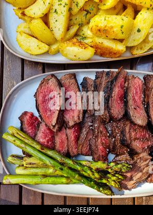 Mittelseltenes Rindersteak auf Teller mit gegrilltem Spargel und gerösteten Kartoffeln Stockfoto