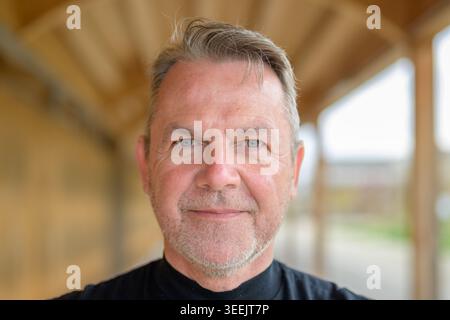 Nahporträt eines ernsten Reifen Mannes mit direktem Augenkontakt und natürlichem Gesichtsausdruck. Authentisches Lifestyle-Bild mit weichem Tageslicht und flacher Oberfläche Stockfoto