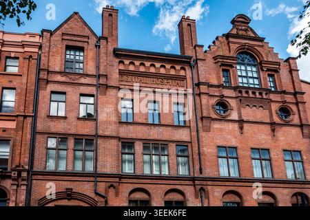 Dublin Dental University Hospital am Lincoln Place, Dublin, Irland. Eine große rote Ziegelfassade mit kunstvollen Giebeln und hohen Schornsteinen unter blauem Himmel. Stockfoto
