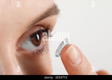 Kontaktlinsen der Zukunft. Frau, die Linse mit digitalen Implantaten ins Auge steckt, Nahaufnahme Stockfoto