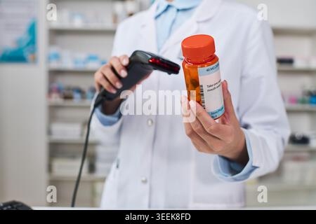 Nahaufnahme eines jungen Apothekers, der den Strichcode für verschreibungspflichtige Pillen in der Apotheke scannt, die Medikamentenausgabe und die Patientensicherheit überprüft. Für Gesundheitswesen, Einzelhandelsapotheke, Versicherungsinhalte Stockfoto