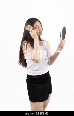 Frau, die Spiegel hält und Make-up auf weißem Hintergrund aufträgt Stockfoto