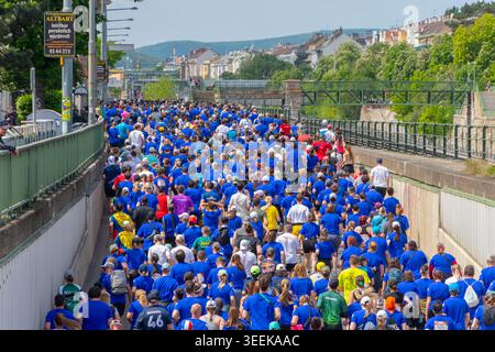 Die Teilnehmer des Sportereignisses bewegen sich während eines großen Laufrennens auf der Stadtstraße, Österreich, Wien, 10. Mai 2026. Stockfoto