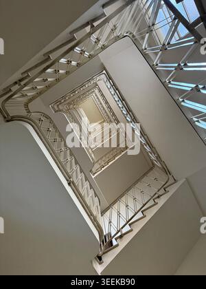 Ein Niedrigwinkelfoto, der direkt durch das Zentrum einer historischen, mehrstöckigen rechteckigen Treppe hinaufblickt Stockfoto