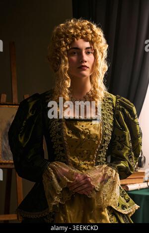Porträt einer jungen Frau, die historisches Kleid und Perücke trägt, im Studio posiert und an Erbe, Luxus und Drama erinnert. Ideal für Kostümgestaltung, Theaterförderung, vertikal Stockfoto