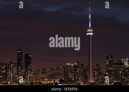 Nächtlicher Blick auf die Innenstadt von Toronto, Ontario, Kanada, mit dem CN Tower und Rogers Centre, hell beleuchtet unter einem violetten und roten Abendhimmel. Stockfoto