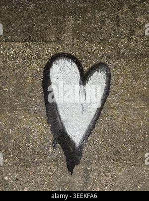 Schwarz-weiß lackiertes Herz auf einer alten Betonwand mit rauer Textur und tropfender Farbe. Stockfoto