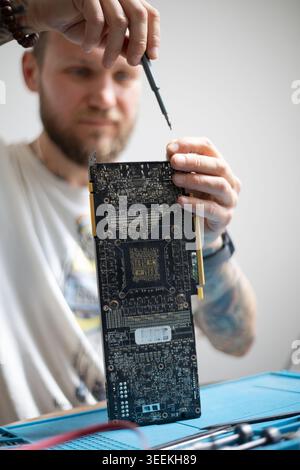 Man arbeitet an der Reparatur von Leiterplatten in einer Heimwerkstatt mit Werkzeugen auf dem Tisch am Nachmittag Stockfoto
