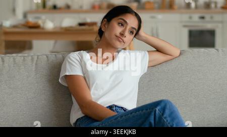Traurig gestresste nachdenkliche indische arabische Frau zu Hause sitzend Sofa denken besorgt weibliche Mädchen Dame müde frustriert gelangweilt Hausbesitzer fühlt sich besorgt Stockfoto