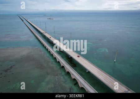 Aus der Vogelperspektive auf den Overseas Highway, der sich über türkisfarbenes Wasser erstreckt, mit Autos und der alten Brücke entlang in Key Largo, Florida, United St Stockfoto