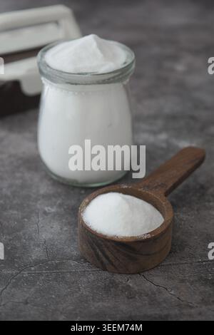 Backnatron Pulver in einem Glas und eine Holzlöffel auf grauer Oberfläche Stockfoto