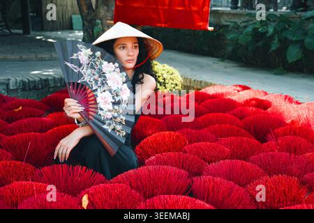Junge Frau in vietnamesischem Hut mit traditionellem Fan Stockfoto
