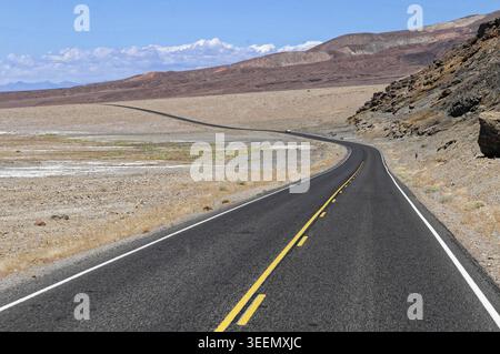 Kurvige Straße schlängelt sich durch trockene Wüstenlandschaft unter blauem Himmel, Country Road, Death Valley, Death Valley National Park, Kalifornien, USA Stockfoto