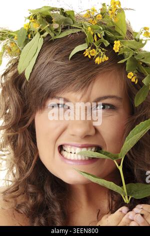 Nahaufnahme Porträt einer schönen wütenden jungen Frau, die Pflanze hält Stockfoto