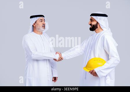Zwei arabische Geschäftsleute in traditioneller Kleidung, die die Hände schütteln, repräsentieren ein erfolgreiches Geschäft, Partnerschaft, Abkommen, Vertrauen und kollabora Stockfoto