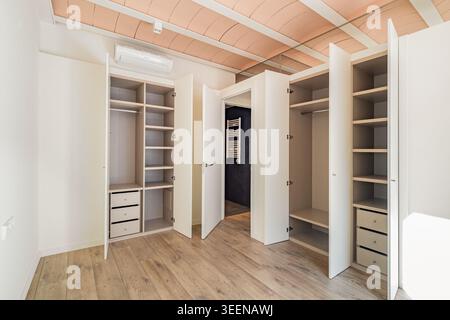 Leerer, moderner Schrank mit offenen Türen, Regalen und Schubladen. Minimalistisches Design mit Holzfußboden und heller Atmosphäre. Stockfoto