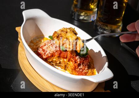 Lasagne Portion, im Ofen gebackene Lasagne, Nudelschichten mit Käse, Hackfleisch, Tomaten. Lasagne am Tisch des Straßenrestaurants an einem sonnigen Sommertag, verschwommen Stockfoto