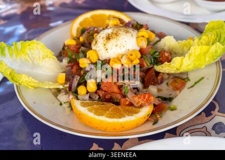 Marokkanischer Salat, auch bekannt als Tabbouleh, Taktouka, Zaalouk oder Shlada mit gemischtem Gemüse, Mais, pochiertem Ei, Orangenscheiben, Salat und Gewürzen Stockfoto
