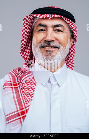Saudischer Senior-Mann, der fröhlich lächelt und ein Porträt eines weisen und selbstbewussten Geschäftsmannes aus dem Nahen Osten in traditioneller nationaler Kleidung präsentiert, s Stockfoto