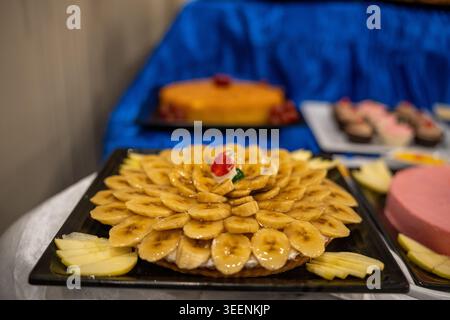 Bananentorte und in Scheiben geschnittene Äpfel auf einem Teller bei einem Dessertbuffet Stockfoto