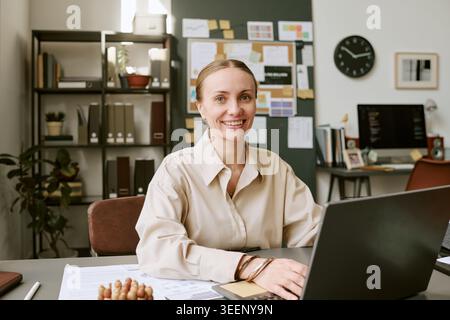 Porträt einer erwachsenen Frau, die im modernen Büro am Laptop arbeitet Stockfoto