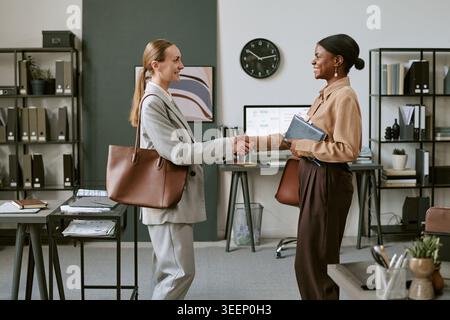 Geschäftsfrauen schütteln sich die Hände während der Partnerschaft für Bürositzungen Stockfoto