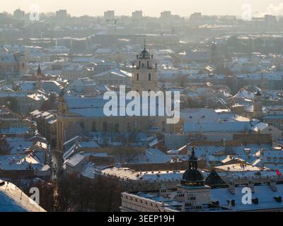 Aus der Vogelperspektive auf die schneebedeckten Dächer und die Kirche St. Johns in der historischen Altstadt unter dem trüben Winterhimmel im Bezirk Vilnius, Litauen. Stockfoto