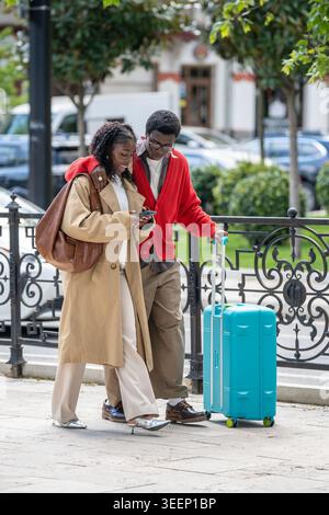 Lächelnde afroamerikaner verheiratete Paare, Männer und Frauen, die auf der Straße in der neuen Stadt spazieren gehen. Stockfoto