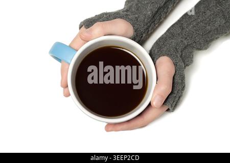 Draufsicht der menschlichen Hände in grauem Strickpullover, der eine blaue Tasse mit schwarzem Kaffee auf weißem Hintergrund hält Stockfoto