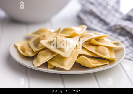 Frische dreieckige Ravioli stapeln sich auf einem Teller aus nächster Nähe und betonen seidige Nudeln, hausgemachte Textur und herzhafte Füllung. Ideal für italienische Rezepte Stockfoto