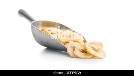 Knusprige Bananenchips und getrocknete Bananenscheiben werden aus einer Metallschaufel auf einen sauberen weißen Hintergrund übertragen und betonen die knusprige Textur, natürliche Frucht ingre Stockfoto