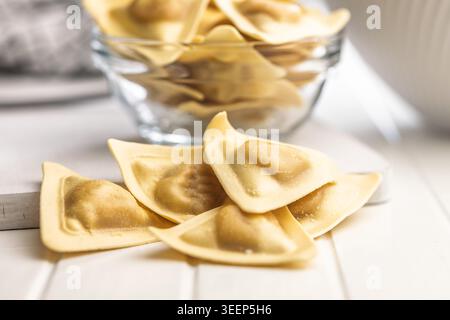 Frische hausgemachte Ravioli-Nudeln auf einem weißen Holztisch, rohe italienische Teigscheiben, die auf eine rustikale Küchenzubereitung hinweisen, authentischer Geschmack, Stockfoto