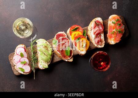 Brushetta oder traditionelle spanische Tapas. Vorspeisen italienische Antipasti-Snacks auf Holzbrett mit Rosen- und Weißwein. Draufsicht und flache Ladefläche mit Platz für Ihren Text Stockfoto