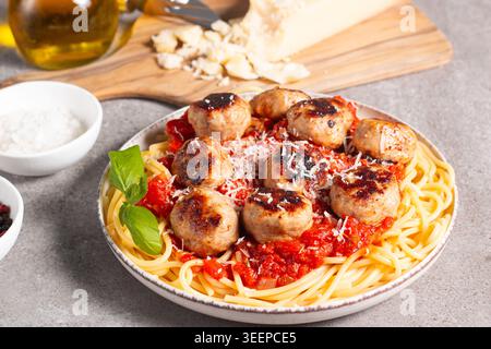Ein Teller mit klassischen Spaghetti, garniert mit gebräunten Fleischbällchen und reichhaltiger Tomatensauce auf einem leichten Keramikgericht. Stockfoto