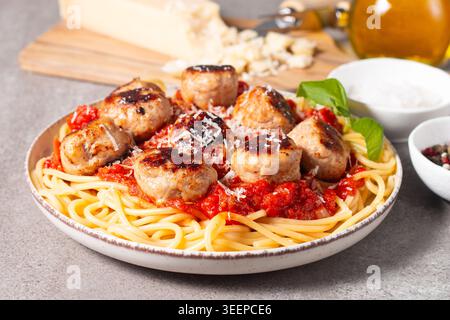 Ein Teller mit klassischen Spaghetti, garniert mit gebräunten Fleischbällchen und reichhaltiger Tomatensauce auf einem leichten Keramikgericht. Stockfoto