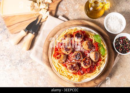 Ein Teller mit klassischen Spaghetti, garniert mit gebräunten Fleischbällchen und reichhaltiger Tomatensauce auf einem leichten Keramikgericht. Stockfoto