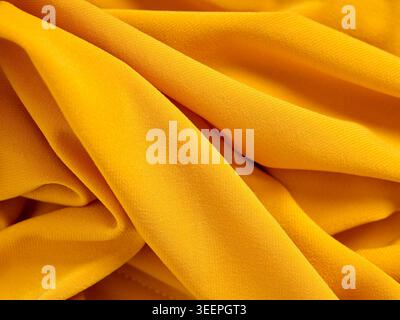 Eleganter gelber Texturhintergrund mit weichen wellenförmigen Falten und detailliertem Textilmaterial aus nächster Nähe Stockfoto