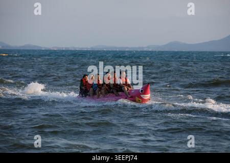 CHONBURI, THAILAND - 2. April 2026: Wassersport-Erlebnis im Sommer mit Touristen auf Bananenbootfahrt, weite Sicht, Pattaya. Stockfoto