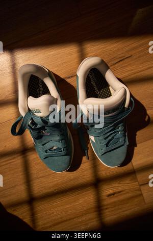 Tyumen, Russland-10. April 2026: POV-Aufnahme von stylischen Adidas-Sneakers unter Schatten von Fensterjalousien, illustratives Editorial Stockfoto