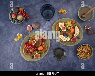 Die Deckenzusammensetzung von Pfannkuchen mit Beeren und Zitrusfrüchten auf dunkler texturierter Oberfläche Stockfoto