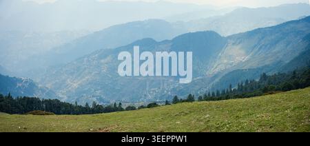 Panoramablick auf mehrschichtige Bergkämme und grüne Wiesen in Raghupur Fort, Sojha, Manali, Himachal Pradesh, Indien. Stockfoto