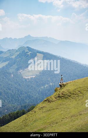 Ein einsamer Wanderer steht auf einem grasbewachsenen Bergrücken mit Blick auf ein riesiges Tal, Raghupur Fort, Sojha, Manali, Himachal Pradesh, Indien. Stockfoto