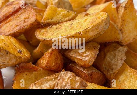 Nahaufnahme von knusprigen gebratenen Kartoffelscheiben mit goldbraunen Gewürzen und rustikaler, gekochter Textur. Stockfoto
