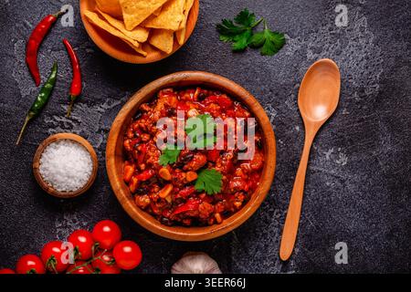 Chili Con Carne in der Schüssel auf dunklem Hintergrund. Mexikanische Küche. Draufsicht Stockfoto
