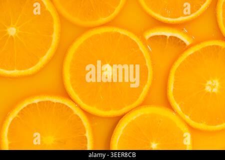 Abstrakter Hintergrund der mit Saft bedeckten Orangenscheiben. Stockfoto