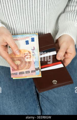 Eine Frau, die eine Brieftasche mit Plastikkarten und Euro-Banknoten hält. Stockfoto