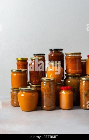Verschiedene Gläser mit hausgemachtem Gemüse stehen zur Vorbereitung auf den Winter an. Die farbenfrohen Gläser zeigen eine Reihe von konservierten Lebensmitteln, die bereit sind Stockfoto