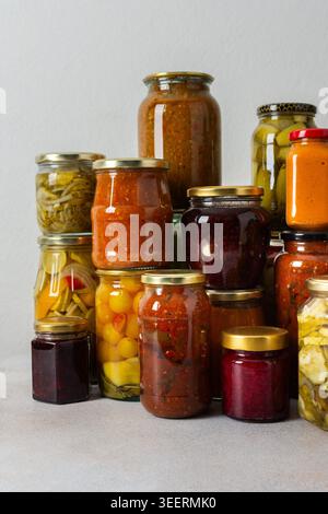 Canning ist eine häufige Aktivität in der Küche, da die Theke mit Gemüse und Obst gefüllte Gläser säumen. Diese Praxis hilft dabei, Lebensmittel für den Gewinn zu bewahren Stockfoto